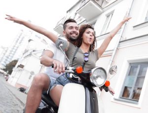 Paar fährt auf Scooter durch die Stadt